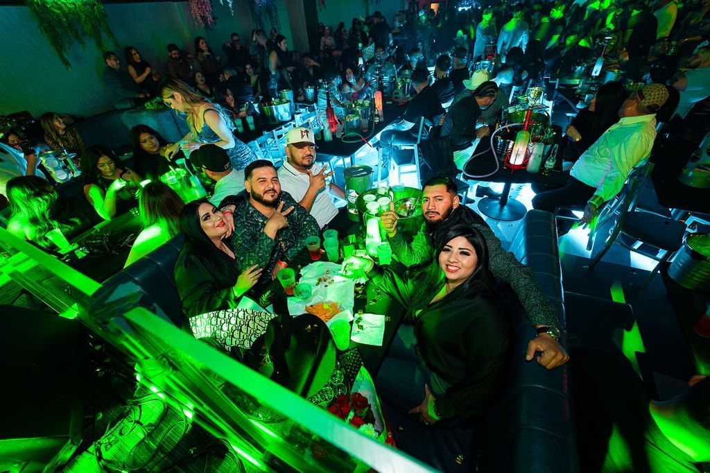 Group of friends celebrating at a table at Zuna Nightclub in Las Vegas under green lights