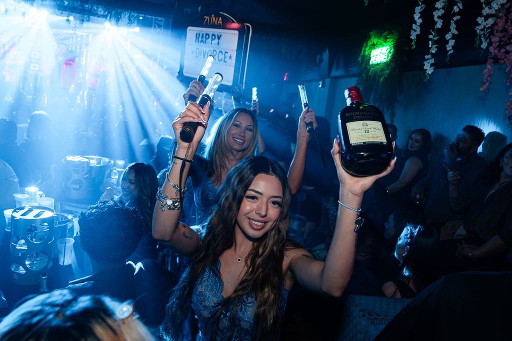 Woman holding up a whisky bottle during bottle service at Zuna Nightclub in Las Vegas